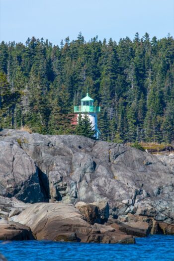 Little River Lighthouse at Western Head Preserve in Cutler, Maine, surrounded by rocky coastline and ocean waves
