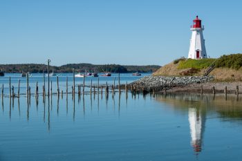 Mulholland Point Lighthouse on Campobello Island, New Brunswick, surrounded by water and a clear blue sky