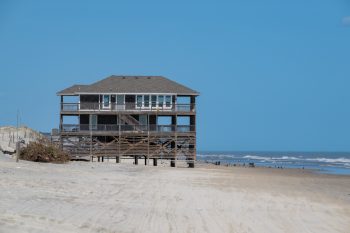 Laughing Gull Beach House in Corolla, North Carolina, showcasing a sunny beach scene with clear blue skies