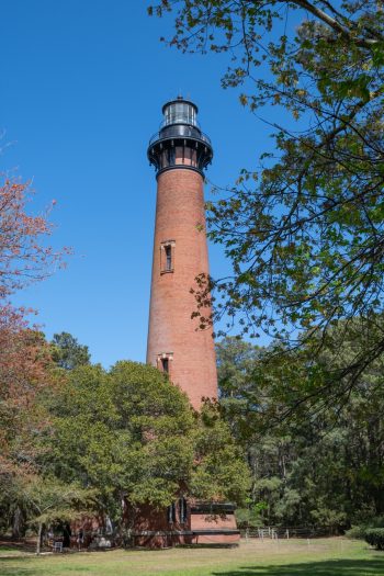Currituck Beach Lighthouse in Corolla, North Carolina, showcasing its tall red brick structure against a clear blue sky